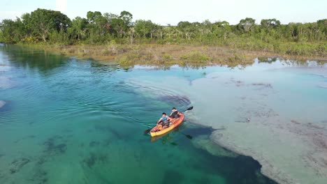 Drone-Aerial-View-of-Couple-Kayaking-in-Bacalar-Lagoon-Lake,-Quintana-Roo-Mexico-on-Sunny-Summer-Day