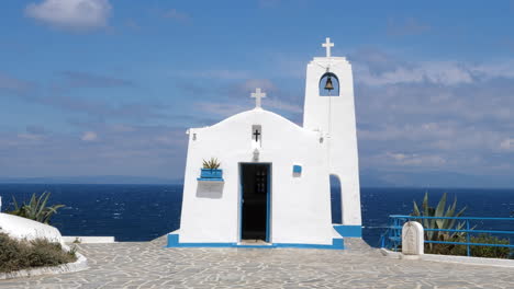 Pequeña-Capilla-Blanca-Junto-Al-Mar-Azul,-Agios-Nikolaos-Rafina-Grecia