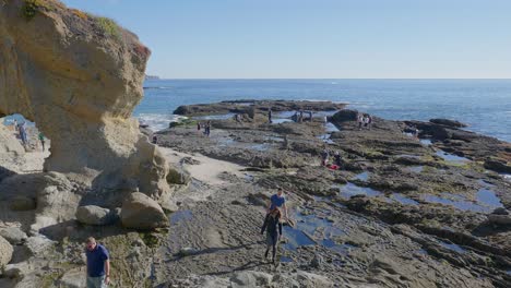 People-exploring-the-coastline-and-tidepools-in-Laguna-Beach,-California
