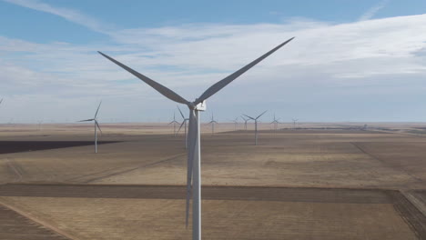 4k-close-up-of-large-wind-turbine-spinning-over-plains-in-North-Texas,-USA-amid-a-mass-wind-farm