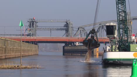Waterway-corridor-leading-underneath-a-bridge-over-river-IJssel-in-the-background-with-heavy-machinery-dredging-ship-in-the-foreground-at-work