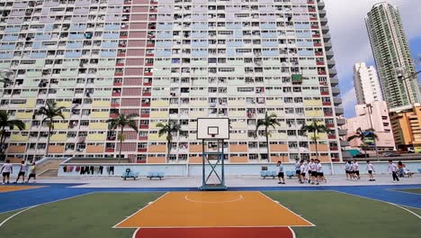 People-Behind-Basketball-Court-in-Front-of-Choi-Hung-Estate-Building,-Hong-Kong,-Static-View