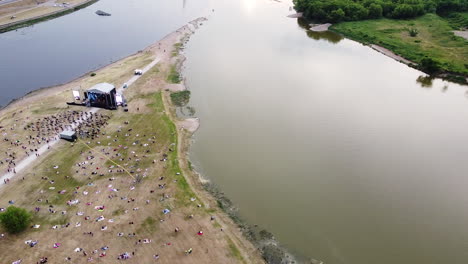 Crowd-of-people-at-music-stage-in-Nemunas-and-Neris-river-conjunction,-aerial-fly-over-view