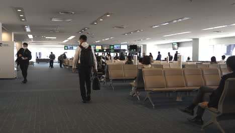 Pasajeros-Sentados-En-Sillas-De-Espera-En-La-Puerta-De-Embarque-Del-Aeropuerto-De-Haneda-Durante-La-Pandemia-En-Tokio,-Japón.