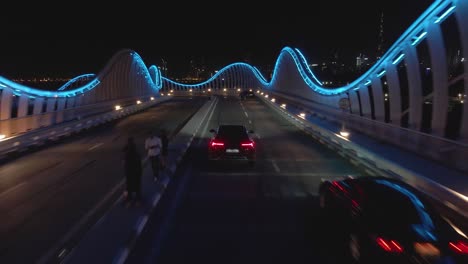 Aerial-track-shot-of-Lamborghini-Urus-drive-illuminated-Meydan-bridge-in-Dubai