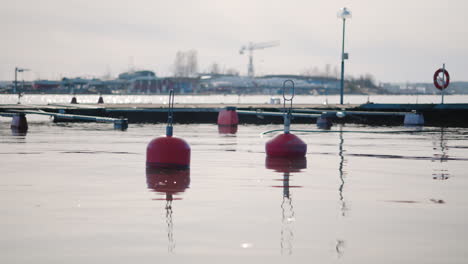 Red-buoys-floating-on-the-water-surface-near-the-shoreline-in-a-port
