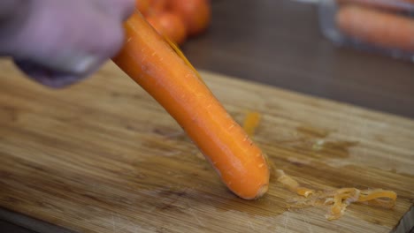 Primer-Plano-Pelando-Zanahoria-Madura-Fresca---Mano-Delante-De-La-Zanahoria-Con-Zanahoria-Enfocada-24fps
