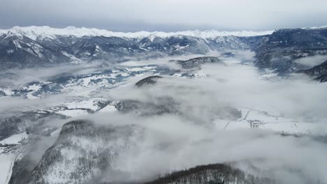 Luftschwenkaufnahme-Winterbergkette-Verschneiter-Gipfel-Nebliger-Bewölkter-Tag