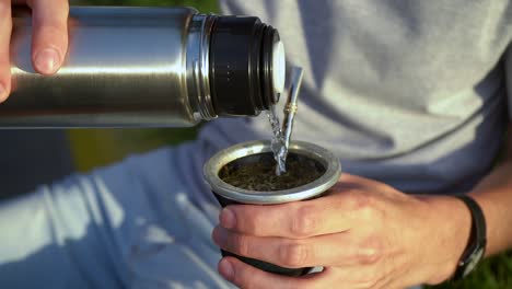 Man-Pouring-Hot-Water-Into-Yerba-Mate-Drink-From-Vacuum-Flask