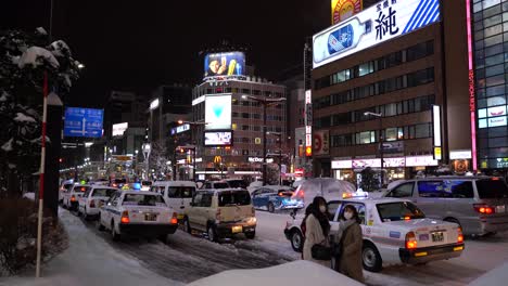Tourists-getting-out-of-Taxi-on-frozen-street-in-snowy-Hokkaido,-Japan