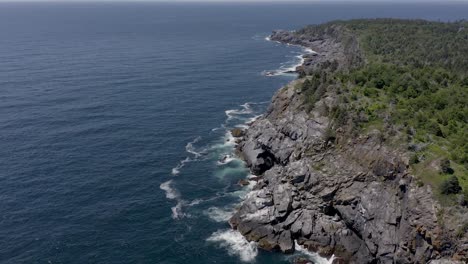 Drone-flying-around-a-cliff-off-the-rocky-coastline-of-a-small-island-in-Maine