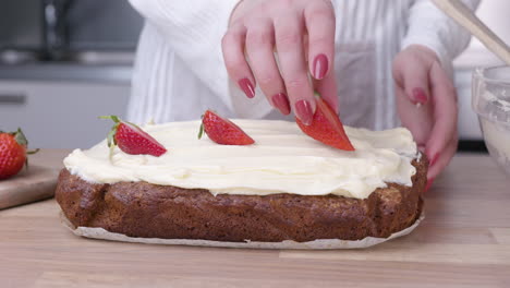 Woman-Putting-Fresh-Sliced-Strawberries-On-Top-Of-The-Baked-Carrot-Cake---close-up