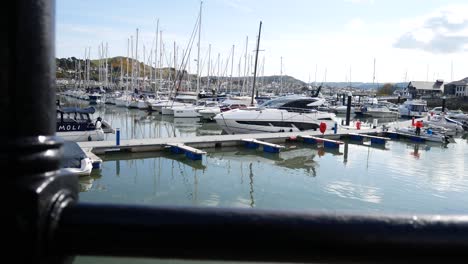 Luxury-sailboats-and-yachts-moored-Conwy-marina-view-through-metal-railings-overlooking-waterfront-North-Wales-right-dolly