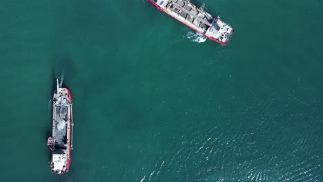 Hoher-Drohnenblick-Mit-Blick-Auf-Die-Umweltauswirkungen-Auf-Ein-Sensibles-Meeresgebiet,-Die-Durch-Das-Manövrieren-Zweier-Großer-Industrieschiffe-Verursacht-Werden