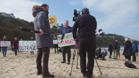 Protesters-being-interviewed-gather-on-the-beach-in-front-of-the-Carbis-Bay-Hotel-in-St-Ives,-Cornwall