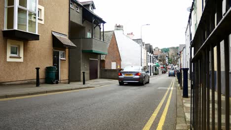 Cars-driving-down-empty-Welsh-Conwy-town-street-towards-castle-landmark