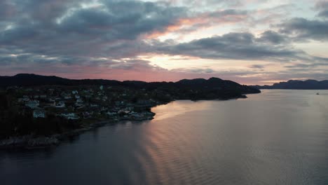 The-town-of-Klokkarvik,-island-Sotra-outside-Bergen---Late-night-dawn-with-dark-foreground-and-red-sunset-skies---Seen-from-Leroyosen-sea