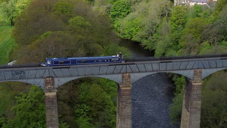Aerial-view-following-narrow-boat-on-Trevor-basin-Pontcysyllte-aqueduct-crossing-in-Welsh-valley-countryside-birdseye-tracking-overfly