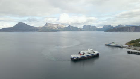 Aerial-shot-of-a-ferry-sailing-on-the-coast-of-Norway-surrounded-by-mountains