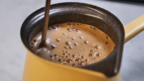 Stirring-fresh-coffee-with-a-spoon-in-coffee-pot-after-adding-fresh-mixed-coffee-beans