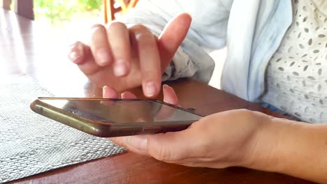 Nahaufnahme-Von-Frauenhänden,-Die-An-Einem-Holztisch-In-Einem-Café-Restaurant-SMS-Schreiben,-Nachrichten-Senden,-Kommunizieren-Und-Mit-Freunden-Auf-Einem-Android-Handy-Sozial-Sind