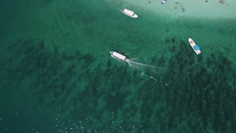 Vertikale-Luftaufnahmen-Eines-Touristenbootes-Im-Klaren,-Flachen-Türkisfarbenen-Wasser
