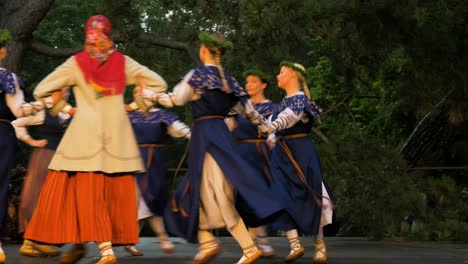 Adult-caucasian-female-dancers-in-traditional-folk-costumes-perform-in-a-dance-performance-in-open-air,-sunny-summer-evening,-happy,-Latvian-national-culture,-handheld-medium-tracking-shot