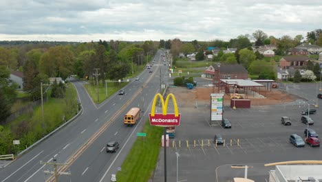 Aerial-dolly-shot-of-McDonald's-sign,-school-bus-and-traffic-on-highway