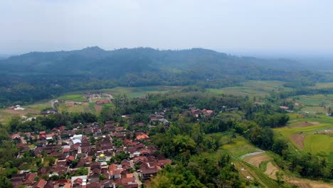 Quiet-village-among-green-hills-on-Java-island,-Indonesia,-aerial-panorama