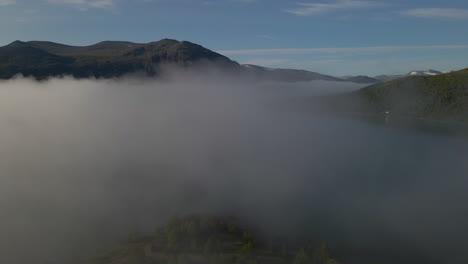 Drone-flying-through-cloud-and-fog-surrounded-by-mountains-and-forests