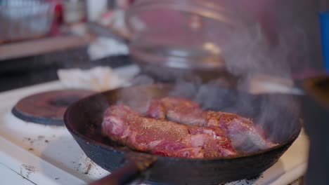 Red-Meat-Smoking-in-Cast-Iron-Skillet-in-Old-Countryside-Kitchen,-Handheld-Medium-Shot