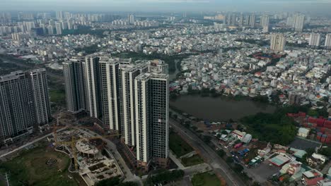 Vuele-Hacia-Un-Gran-Desarrollo-Residencial-De-Viviendas-De-Gran-Altura-En-El-Sudeste-Asiático-Con-Una-Expansión-Urbana-Al-Fondo