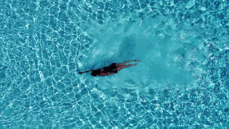 Vogelperspektive-Einer-Frau,-Die-Am-Pool-Schwimmt---Drohnenaufnahme
