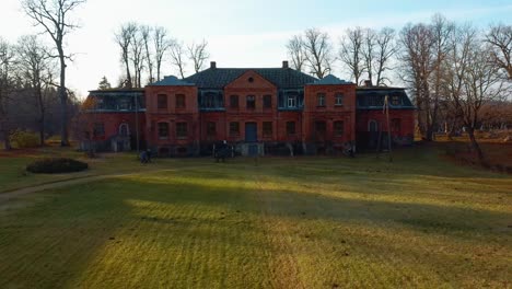 Antigua-Casa-De-Ladrillo-Rojo,-Señorío-Katvari-En-Letonia-Y-El-Lago-Katvaru-Al-Fondo