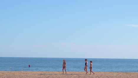 Young-tourists-in-swimsuits-walking-along-the-beach-and-enjoying-their-vacation