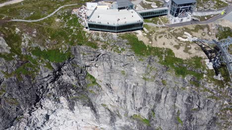 Spectacular-viewpoint-on-edge-of-mountain-Hoven-cliff---Loen-skylift-building-approaching-aerial-with-tilt-down---Top-down-view-of-steep-cliff-and-building-at-edge---Norway