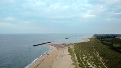Aerial-shot-flying-backwards-over-an-empty-beautiful-beach-on-a-UK-coastline