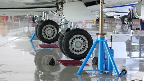 Biz-jet-aircraft-on-jacks-during-maintenance,-zoom-in-on-undercarriage