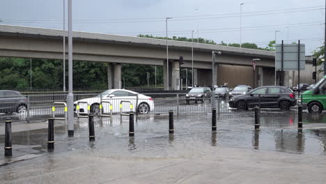 Vehicles-drive-through-floodwater-at-a-junction-as-more-water-pours-across-a-pavement-following-thunderstorms-that-saw-a-monthâ€™s-worth-of-torrential-rain-fall-in-several-hours-across-the-capital
