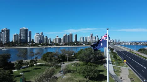 Unique-view-of-a-flag-waving-in-a-strong-breeze-above-a-park-with-a-modern-architectural-skyline-backdrop