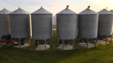 4k-drone-orbiting-around-several-big-grain-bins-standing-in-a-half-circle-on-small-family-operated-farm-in-US-American-countryside