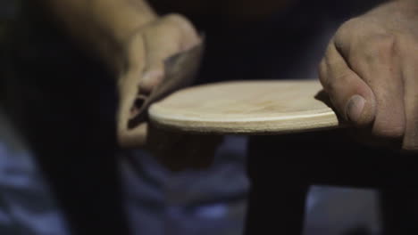 Close-up,-man's-hands-manually-sanding-side-of-DIY-skateboard-wooden-plank-with-sandpaper