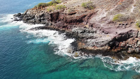 Drone-hovering-over-the-ocean,-looking-down-the-shoreline-in-Maui,-Hawaii