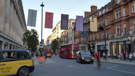 Traffic-Driving-At-Oxford-Street-With-Pedestrians-Walking-On-Sidewalk-In-London,-UK