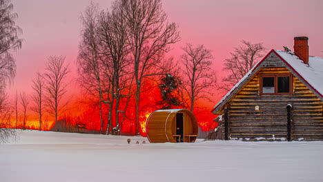 Time-lapse-intense-orange,-red-and-yellow-sunset-with-cabin-and-barrel-sauna