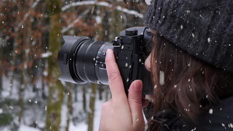 Woman-taking-photos-of-winter-forest-during-heavy-snowfall,-close-up-view