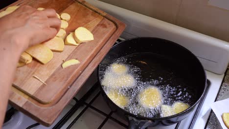 Hand-Putting-Sliced-Sweet-Potato-Chips-Into-A-Frying-Pan-With-Hot-Cooking-Oil