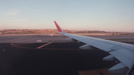 Rollen-Auf-Der-Landebahn,-Aufgenommen-Aus-Dem-Inneren-Des-Flugzeugs-Während-Des-Sonnenuntergangs-Am-Flughafen-Madrid-Barajas-Adolfo-Suárez