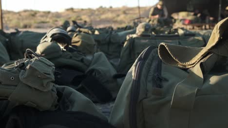 Close-up-of-military-bags-and-military-equipment-lying-in-the-sun-in-the-middle-of-the-desert