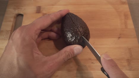 Man-Cutting-Ripe-Avocado-In-Half-By-Fruit-Knife
